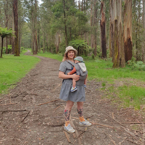 Mother carrying baby in a baby carrier on a path, going for a walk in the mountains